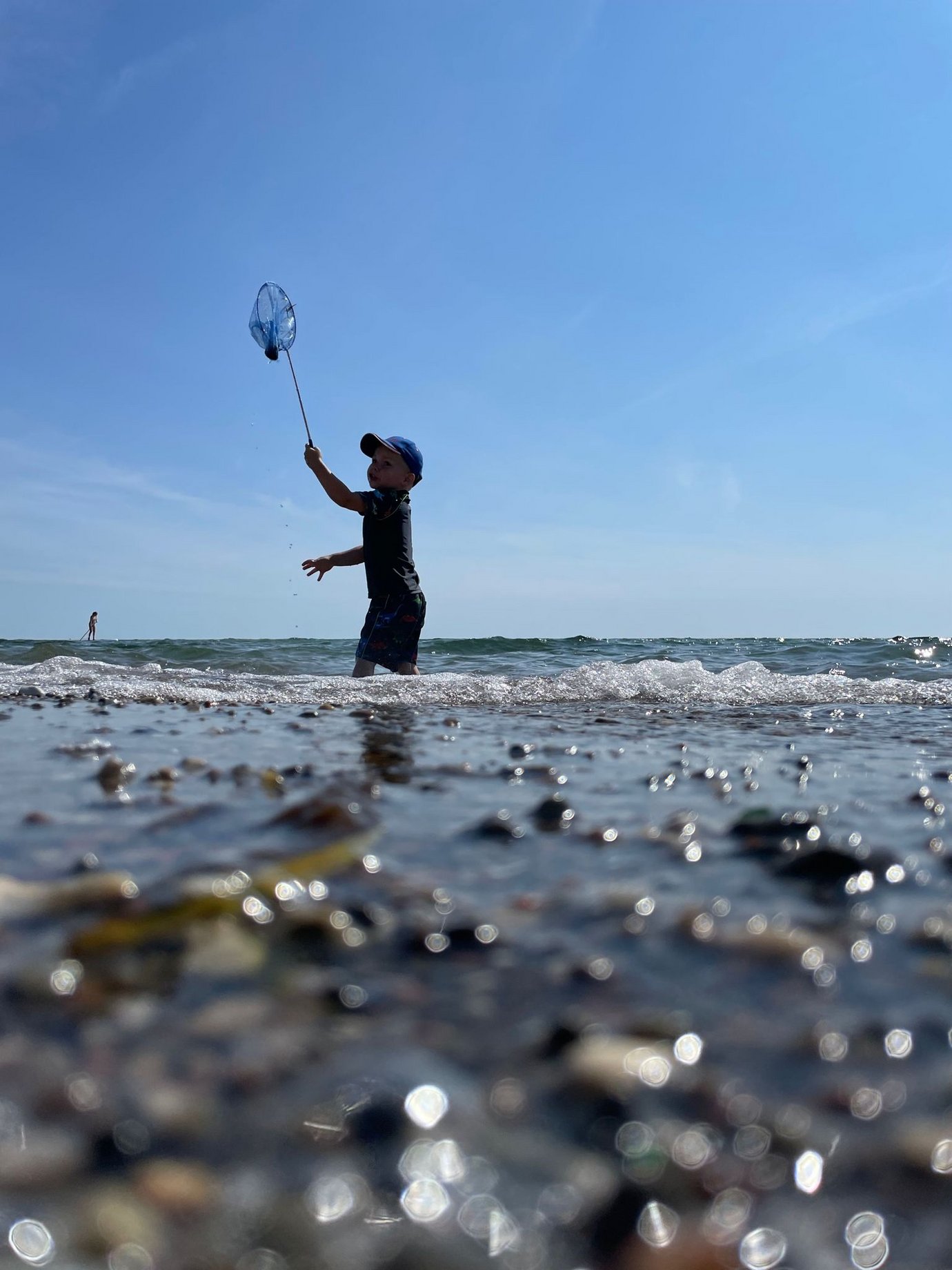 Ein Junge spielt am Strand mit einem Kescher