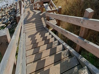 Eine hölzerne Treppe führt die Steilküste hinab ans Meer