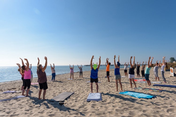 Eine Gruppe von Menschen in Sportkleidung macht Gymnastik am Strand
