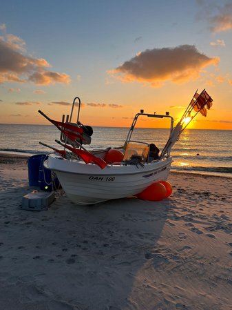 Ein Holzboot liegt bei Sonnenuntergang am Sandstrand