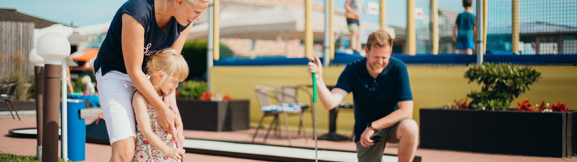 Ein Mutter bringt ihrer kleinen Tochter Minigolfspielen bei